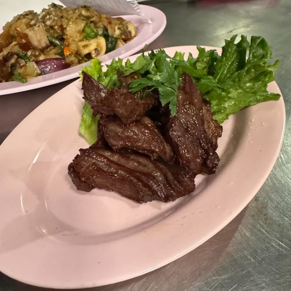 BOK BOK BABY BURIRAM's Thai fried beef with lettuce and cilantro, with another dish in the background.